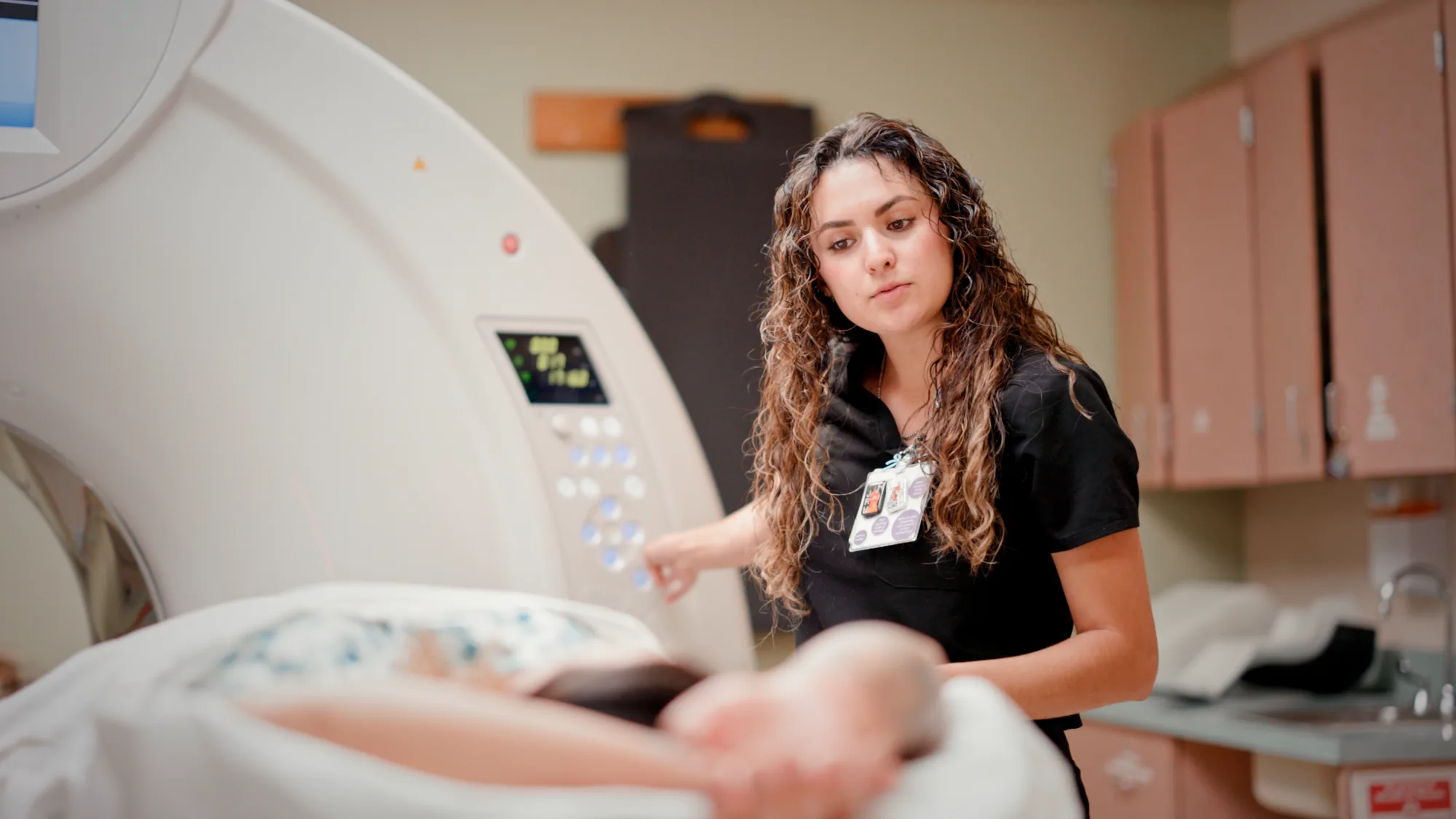 Imaging technician beside a CT scanner